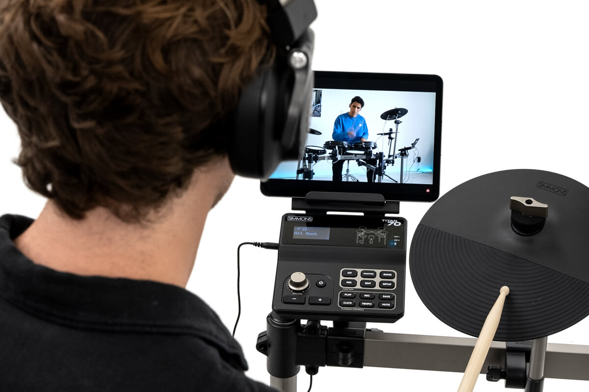 image of drummer playing along to a lesson with a tablet connected to the simmons titan 70 electronic drum kit